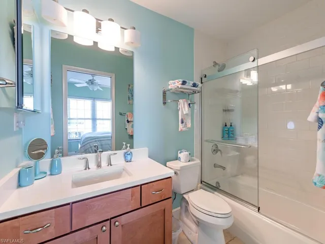 Ensuite bathroom featuring bath / shower combo with glass door, toilet, ensuite bath, ceiling fan, and vanity