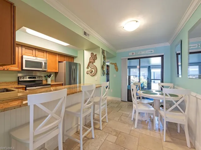 Kitchen with crown molding, stone tile floors, visible vents, appliances with stainless steel finishes, and a kitchen bar