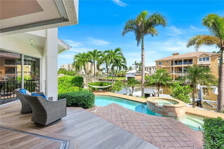 View of swimming pool featuring a patio area, a pool with connected hot tub, and a water view