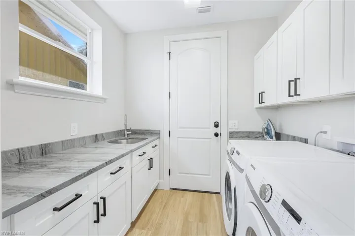 Laundry room with cabinet space, light wood-type flooring, and separate washer and dryer