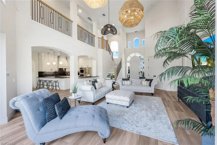 Living room featuring wood finished floors, a chandelier, stairs, a towering ceiling, and recessed lighting