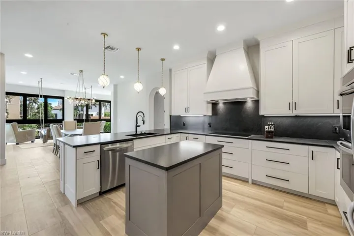 Kitchen featuring custom range hood, pendant lighting, backsplash, a peninsula, and a chandelier