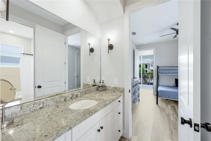 Full bathroom with vanity, ceiling fan, light wood-type flooring, and connected bathroom