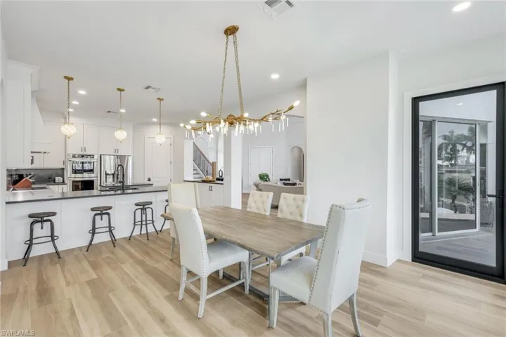 Dining room with light wood-type flooring, a chandelier, stairway, and recessed lighting