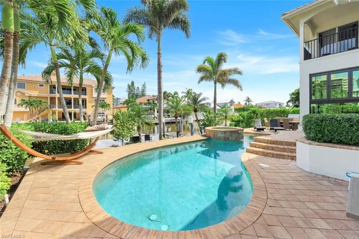 View of pool with a patio and a pool with connected hot tub