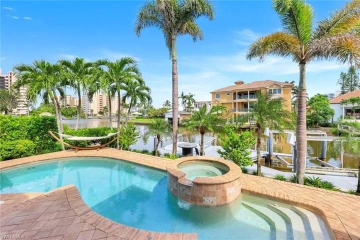 View of swimming pool with a water view, a pool with connected hot tub, and a patio