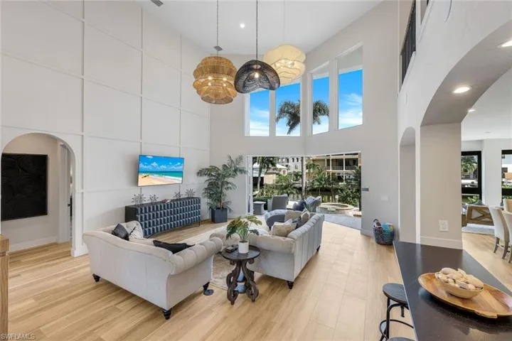 Living room featuring arched walkways, light wood-style flooring, recessed lighting, and a towering ceiling