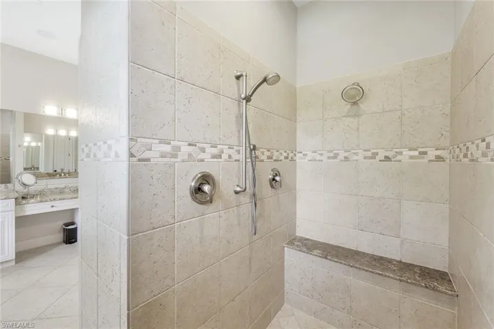 Full bath with walk in shower, vanity, and light tile patterned flooring