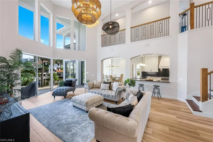Living area featuring a chandelier, arched walkways, stairway, light wood-type flooring, and a towering ceiling