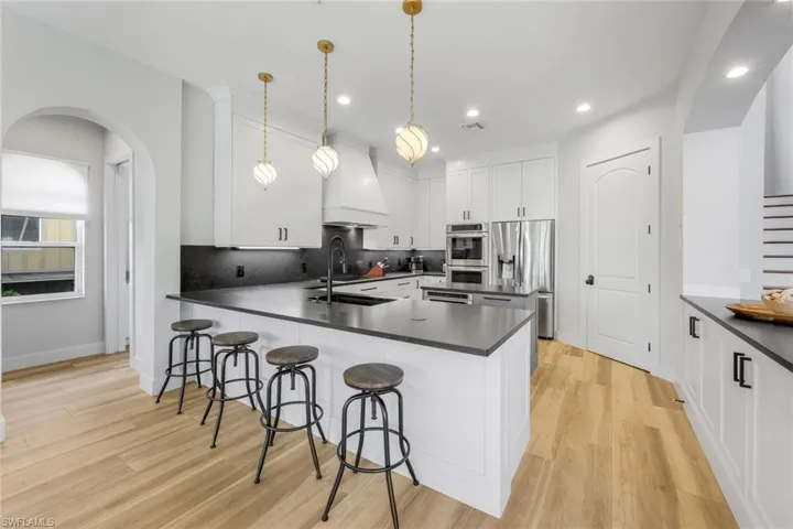 Kitchen with arched walkways, dark countertops, tasteful backsplash, and recessed lighting