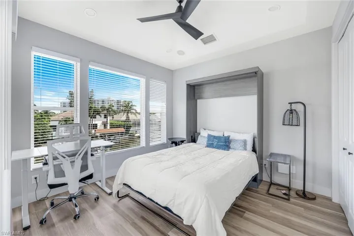 Bedroom with light wood-style floors, a ceiling fan, an office area, and recessed lighting