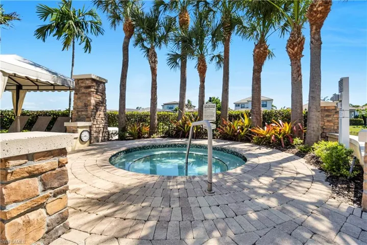 Circular hot tub featuring an integrated handrail, surrounded by paver stone decking