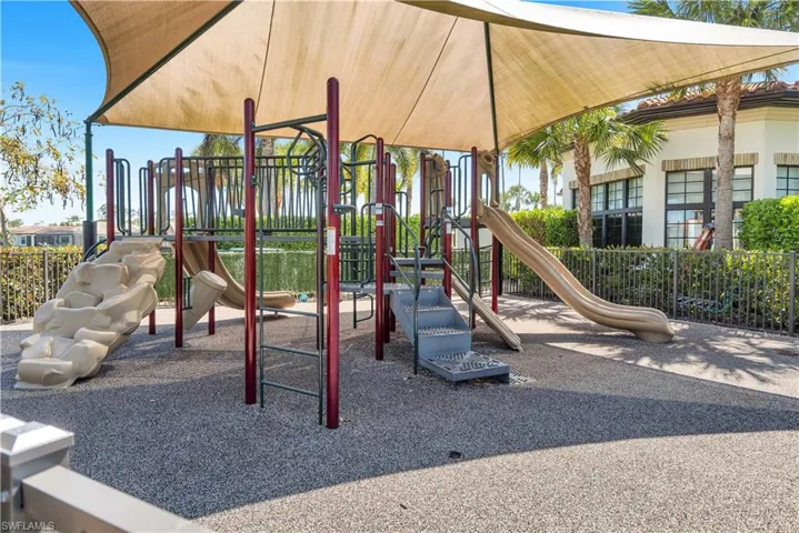 Outdoor playground featuring multiple slides, climbing structures, and a protective shade canopy