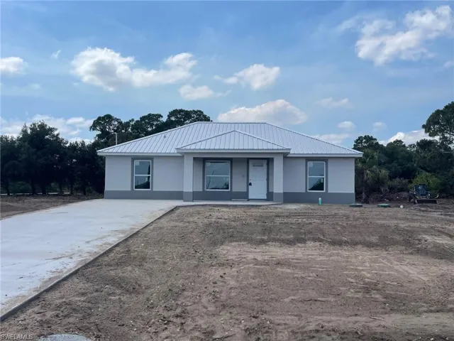 Ranch-style house featuring stucco siding, metal roof, and covered porch
