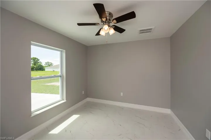Spare room featuring marble finish floor, a ceiling fan, visible vents, and baseboards