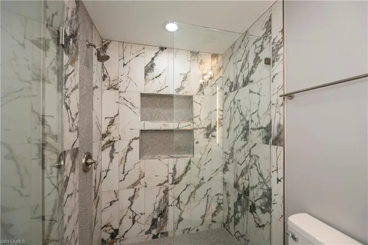 Full bath featuring a marble finish shower and toilet
