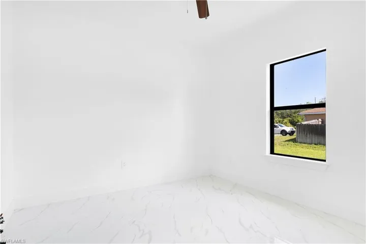 Empty room with marble look tiles, baseboards, and ceiling fan