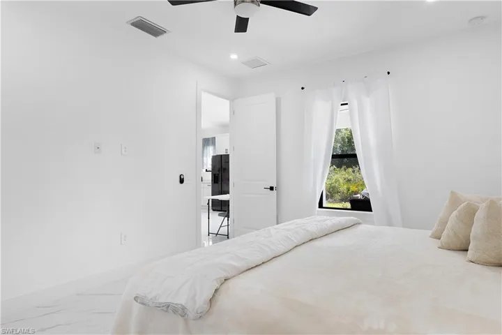 Bedroom with marble look tiles, recessed lighting, ceiling fan, and baseboards