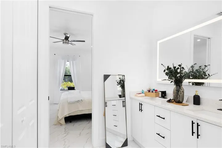Bedroom featuring light marble finish flooring, a sink, and a ceiling fan