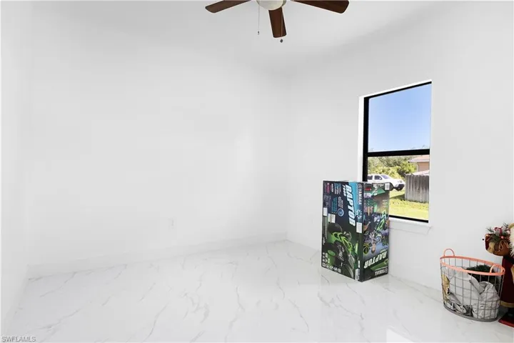 Spare room featuring marble look tiles, baseboards, and a ceiling fan