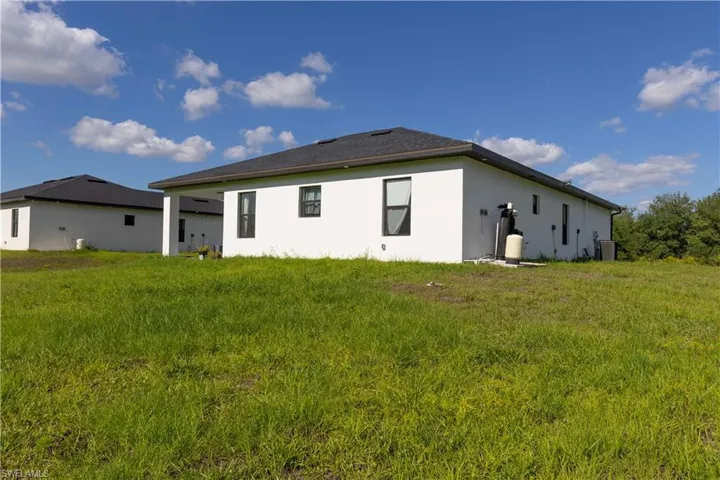 Back of property with stucco siding and central AC unit