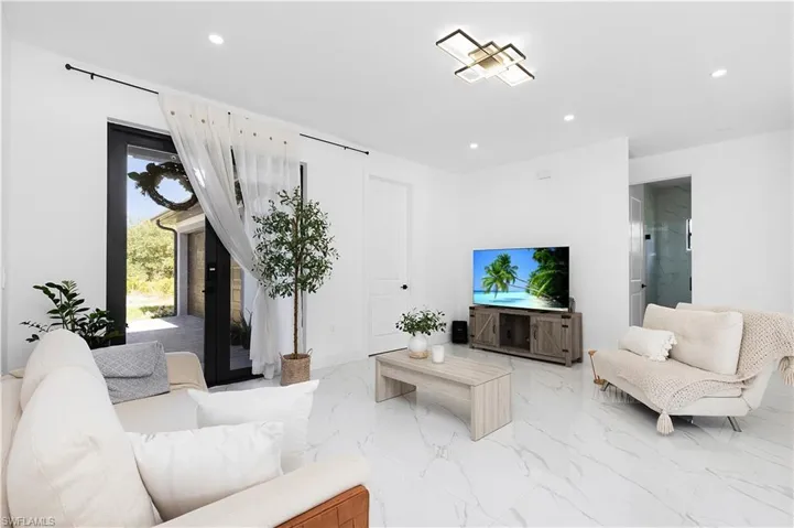 Living room with recessed lighting and light marble finish floors