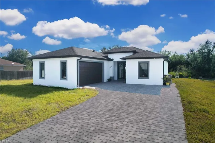 View of front of property featuring a garage, stucco siding, and decorative driveway