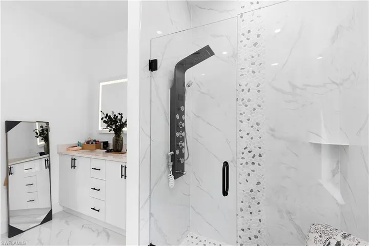 Full bathroom featuring a marble finish shower, vanity, and marble finish floors
