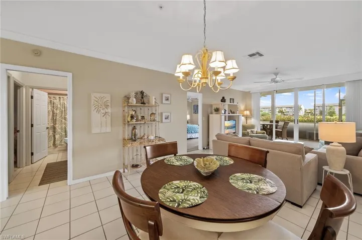 Dining space featuring crown molding, light tile patterned flooring, ceiling fan, and a chandelier