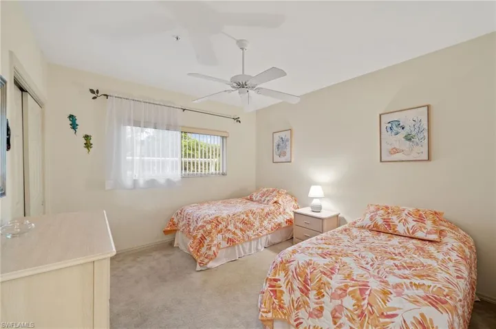 Carpeted bedroom with ceiling fan and a closet