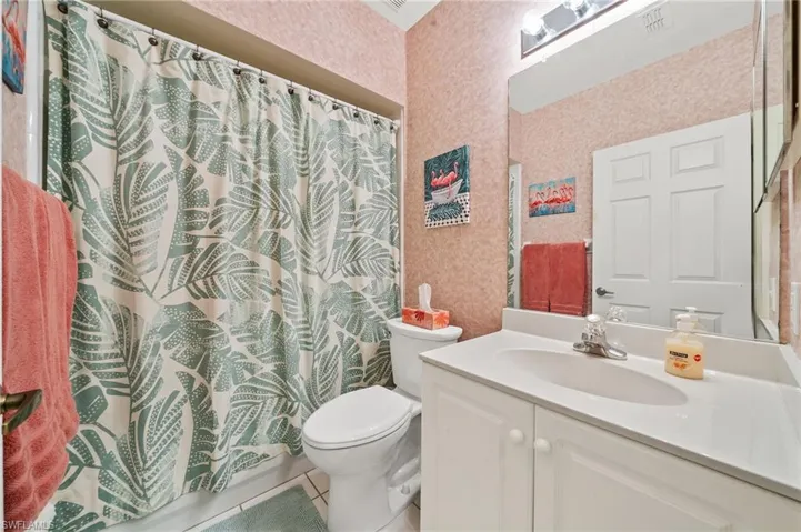 Full bathroom featuring vanity, light tile patterned flooring, wallpapered walls, and shower / tub combo with curtain