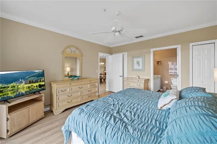 Bedroom with crown molding, light wood-style floors, ceiling fan, a closet, and ensuite bathroom
