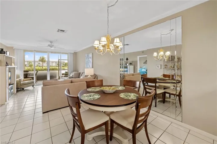 Dining room with crown molding, a ceiling fan, light tile patterned flooring, floor to ceiling windows, and a chandelier