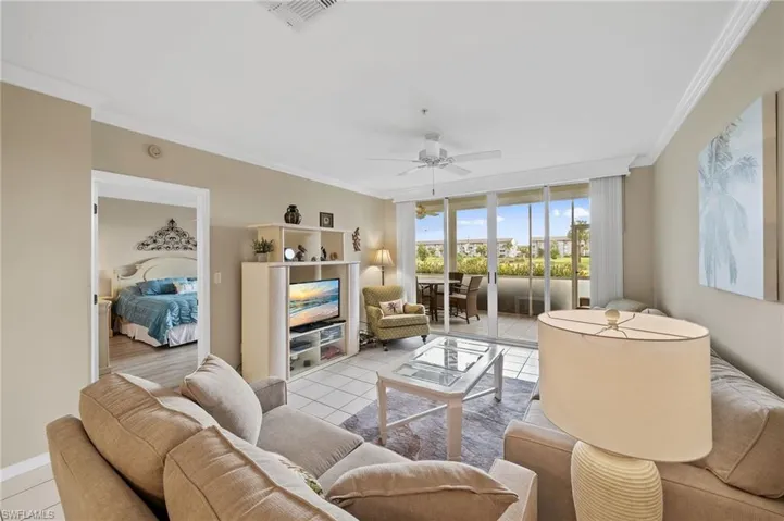 Living room with light tile patterned floors, a wall of windows, crown molding, and a ceiling fan