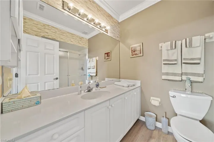 Full bath with ornamental molding, a shower stall, vanity, and light wood finished floors