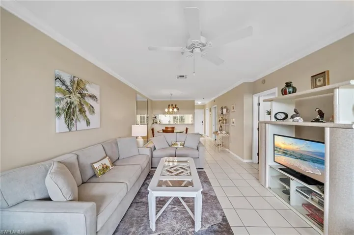 Living area featuring ornamental molding, light tile patterned flooring, a chandelier, and a ceiling fan