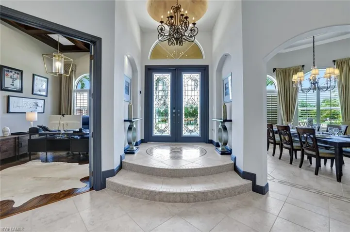 Foyer featuring a chandelier, light tile patterned floors, french doors, and a high ceiling