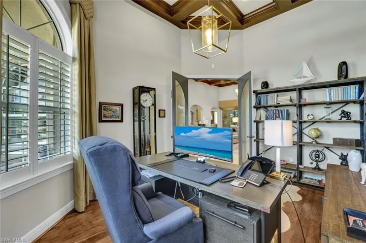 Office area with dark hardwood flooring, coffered ceiling.