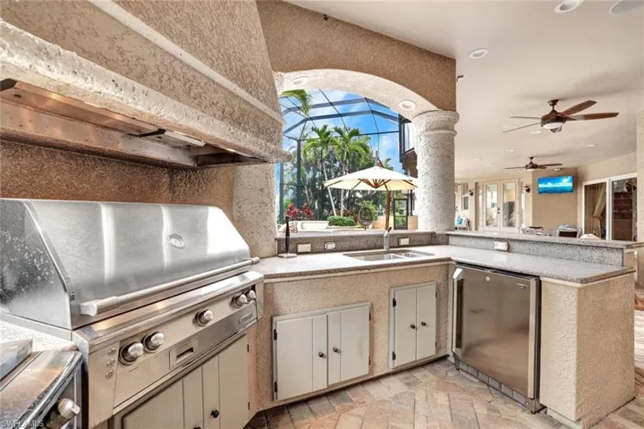 Summer kitchen w/built in gas grill with additional burners, prep sink and refrigerator.