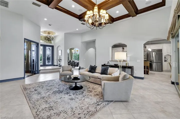 View from the back of the spacious Great Room with chandelier, coffered ceiling, formal dining to the right of front entry.