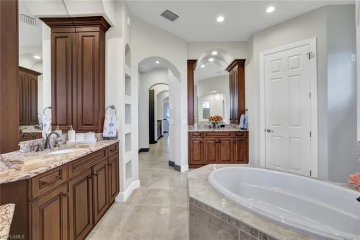 Bathroom with tiled tub, vanity, and tile patterned flooring
