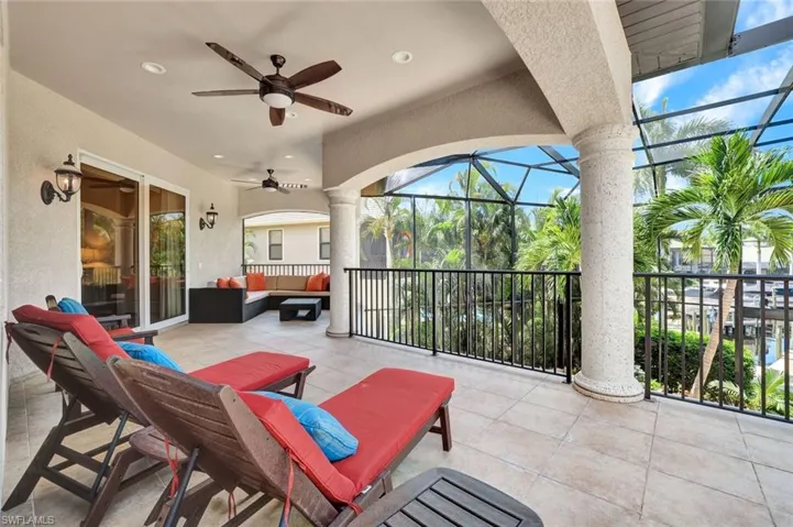 View of 2nd story screened balcony with outdoor lounge area, multiple seating areas and ceiling fans. Sliders lead to 5th bedroom