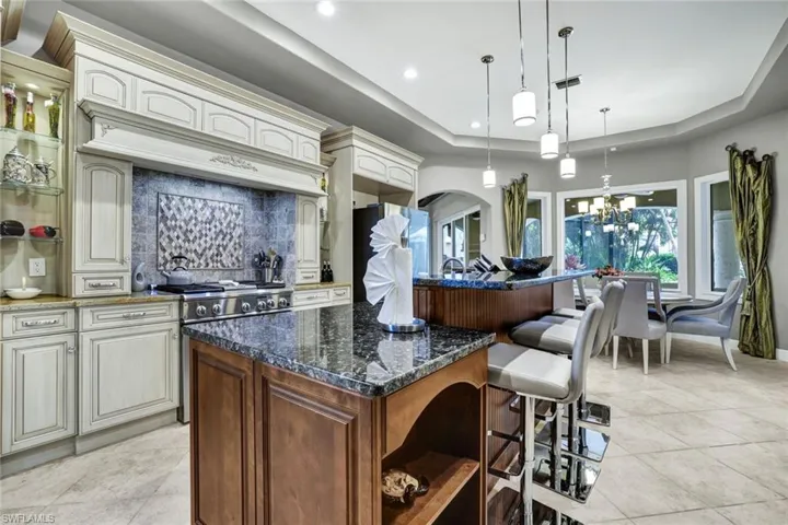 Kitchen featuring granite countertops, backsplash, pendant lighting, and a raised ceiling