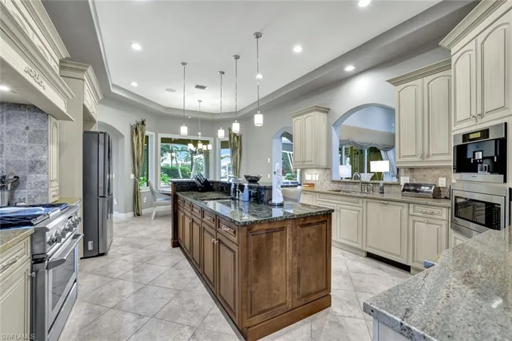 Kitchen featuring decorative light fixtures, granite countertops, a kitchen island, appliances with stainless steel finishes, and backsplash