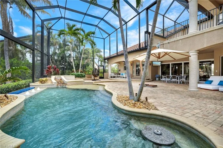 View of pool, spa & waterfall, sun shelf, built in table and seating area.