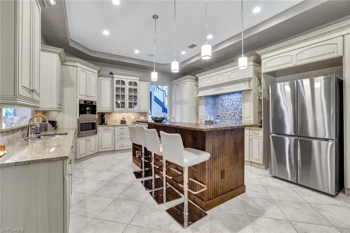 Kitchen with a kitchen island, a tray ceiling, stainless steel appliances, decorative backsplash, and sink