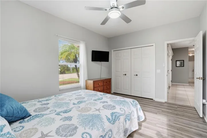 Bedroom with ceiling fan, light wood-style flooring, and a closet