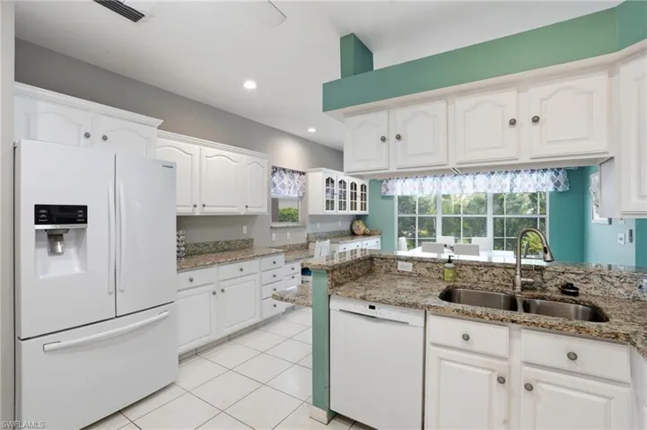 Kitchen with white appliances, white cabinetry, light stone countertops, a peninsula, and glass insert cabinets