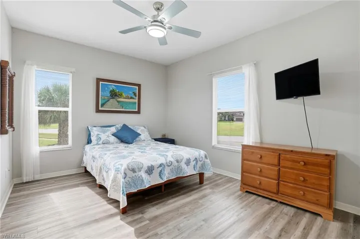 Bedroom featuring ceiling fan, multiple windows, and light wood finished floors