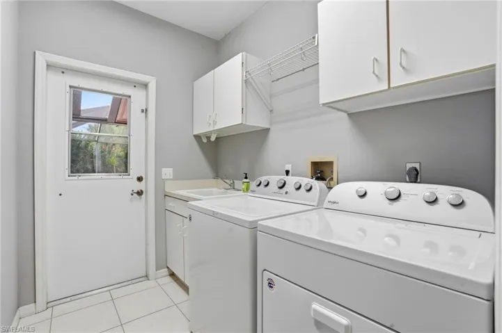 Laundry area with cabinet space, light tile patterned floors, and independent washer and dryer